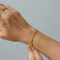 Detail van een 18K vergulde roestvrijstalen platte slangenarmband om de pols gedragen - 2mm Blade Slangenketting Armband