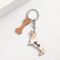 Detailopname van de teckel moeder sleutelhanger met bot hanger en metalen ring - Witte Honkbal
