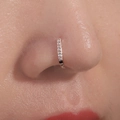 Close-up of a rose gold nose ring with sparkling diamonds on a model's nose - U-Shape With Zirconia / Rose Gold
