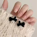 Close-up of elegant black velvet bow earrings with white pearls held against a sweater - Style 19 Bowknot Pearl Studs with Silver Post / Black