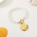 Detalle de una pulsera de perlas de verano con estrellas de mar doradas y cierre tipo OT - Concha con Patrón Radiante (KB203122-SXSJ)