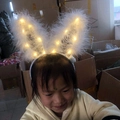 LED rabbit ear headband with white feathers shown in a dimly lit setting for kids - Bunny Ear Headband / 14 LED White + Warm Light