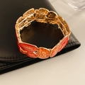 Macro di un bracciale vintage dorato con trama a fragola in smalto rosso e arancione - Oro-Rosso-Arancione