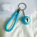 Detail of blue mini pool ball keychain with number 7 and woven strap hanging on a metal ring - No.7 (Dark Blue)