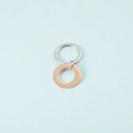 Dettaglio di pendenti circolari lucidi in argento e oro rosa su uno sfondo azzurro - Oro rosa