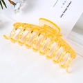 Macro shot of large yellow transparent plastic hair claw clip on white textured cloth - Jelly Transparent Orange