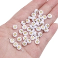 White and gold round acrylic letter K bead for DIY jewelry making held in palm - Letter K