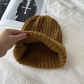 Winter chunky knit beanie in ginger yellow color laying on a white textured fabric - Coffee
