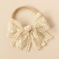 Detailed close-up of beige baby headband with intricate floral lace embroidery bow - Off White