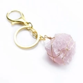 Detalle macro de gema de cristal rosa natural envuelta en hilo dorado con llavero mosquetón - Cuarzo rosa