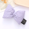 Purple pleated leather bow accessory with creative white text label on white surface - Purple