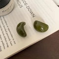 Primer plano detallado de pendientes de resina verde oscuro sobre un libro abierto - Verde