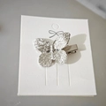 Barrette à cheveux papillon élégante en métal argenté présentée sur carte blanche - Papillon Unique