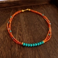 Detail of three-layer beaded necklace with red faceted beads and turquoise accents - Orange & Blue Geometric Style