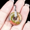 Polished natural green aventurine donut pendant with silver bail on black background - 20mm Unakite
