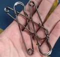 Three gunmetal gray oversized metal safety pins for scarves held in a palm for size - Gunmetal