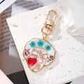 Artistic resin face keychain with colorful dried flowers on a white stone background - Blue Three Flowers