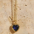 Macro shot of a gold necklace featuring a deep blue heart-shaped gemstone pendant - Royal Blue