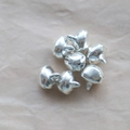 Vista macro di accessori campanelli in metallo argentato su sfondo di carta marrone - 6mm / Argento