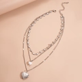 Dettaglio della collana argentata a tre strati con perla a cuore e ciondoli con rilievo - Argento