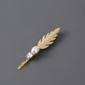 Elegante pasador de pluma dorada con diamantes de imitación y perla sobre gris liso - Dorado