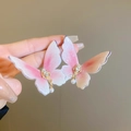 Dettaglio di orecchini a farfalla con glitter rosa e pendenti di perle - Rosa
