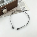 Detail of a black wavy metal headband with soft protective tips on a minimalist background - Spring Headband / Black