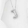 Macro shot of silver balloon letter J pendant with beaded chain on white velvet - Letter J Pendant