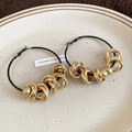 Detail of oversized black metal hoop earrings with gold woven knots on a white plate - S925 Silver Pin / Gold (Earrings)
