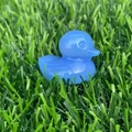 Translucent blue crystal duck figurine carved from natural stone on a green grass lawn - Blue Opalite