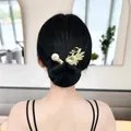 Détail d'une pince à cheveux cygne dorée avec zircons et perle sur un chignon élégant - Paon Goutte d'Eau Or