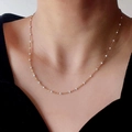 Minimalist gold titanium necklace with white enamel beads shown on a model neck - White