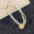 Dettaglio della collana di perle multistrato con ciondolo a fiore di camelia con diamanti - Stile Camelia Perla a Tre Strati / Oro-Bianco