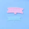 Close-up of pink silicone baby letter mold with finished light blue fondant banner decoration - BABY Banner