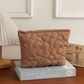 Pochette trucchi marrone trapuntata a fiori con cerniera su sfondo di libri vintage - caffè
