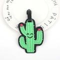 Green cactus silicone luggage tag with a smiling face and black strap on a white plate - Cactus
