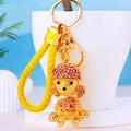 Detailed close-up of a rhinestone puppy keychain with a yellow braided rope and gold ring - Yellow Rope + Poodle Champagne