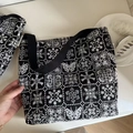 Close-up of black and white butterfly embroidery patterns on canvas tote bag fabric - Large Underarm Bag