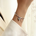 Detailed view of a silver heart charm bracelet worn by a model in soft lighting - 15+5cm / Silver Bracelet