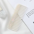 Close-up of a pearlescent white acetate wide-tooth comb on a silk and book background - 11.8*4.6cm / Mermaid Iridescent