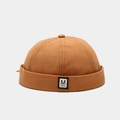 Macro detail van het M FASHION label op de oranje-bruine canvas docker hat met textuur - Verstelbaar / Oranje