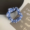 Blue floral fabric scrunchie with elastic design on white surface with props - Blue Floral