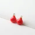 Macro shot of red pomegranate resin pendants with gold rings for DIY jewelry making - Whole Pomegranate