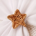 Macro shot of hand-woven rattan star napkin ring showing natural texture on white cloth - Star