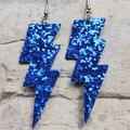 Dettaglio di orecchini a saetta con glitter blu su sfondo testurizzato - Paillettes Blu