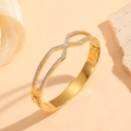 Detail of gold titanium steel bangle featuring a crisscross design and pavé cubic zirconia - Gold Hollow Cross X-Shape Style (M812)