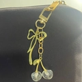 Detail of a shiny gold keychain with glitter-filled cherry and bow charms - Gold Bow Glitter Cherry