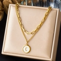 Detailed macro view of gold layered necklace featuring a moon pearl pendant on a beige box - Double Layer Chain with Shell Moon Round Pendant Style (N4111)
