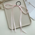 Detail shot of elegant pink satin bow hair tie with long ribbons on a decorative tray - Pink