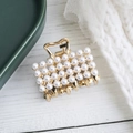 Elegante pinza de pelo de metal dorado con perlas blancas sobre una superficie de madera - Cuadrado Dorado